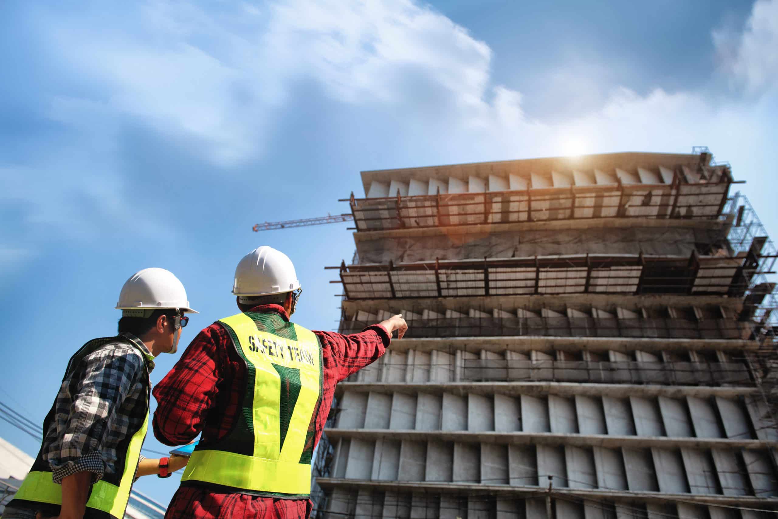 Construction engineers discussion with consultant at construction site or building site of highrise building with blueprints. CIS Payroll London