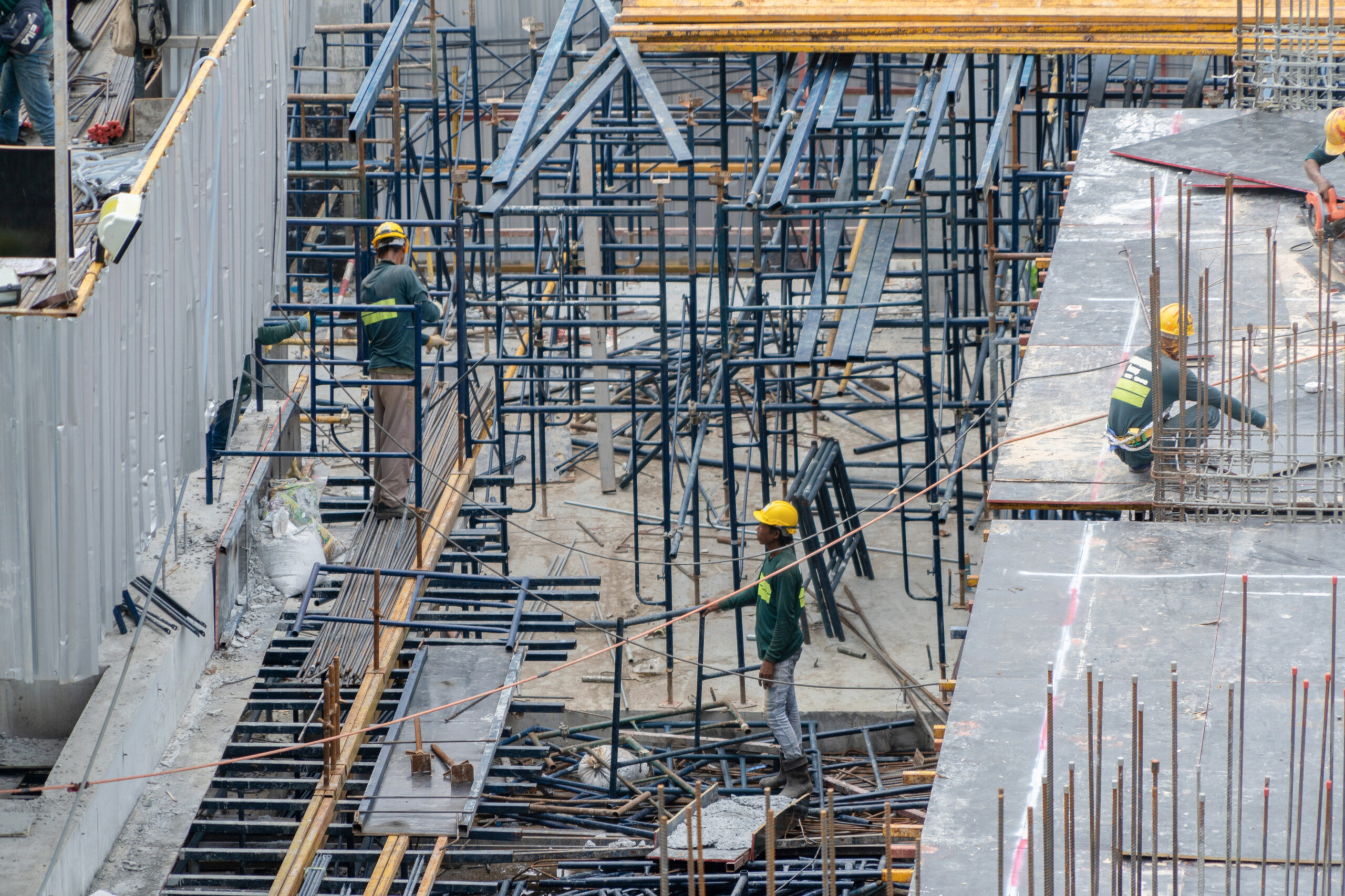 Aerial view of busy industrial construction site workers with cranes working. Top view of development high rise architecture building at noon.