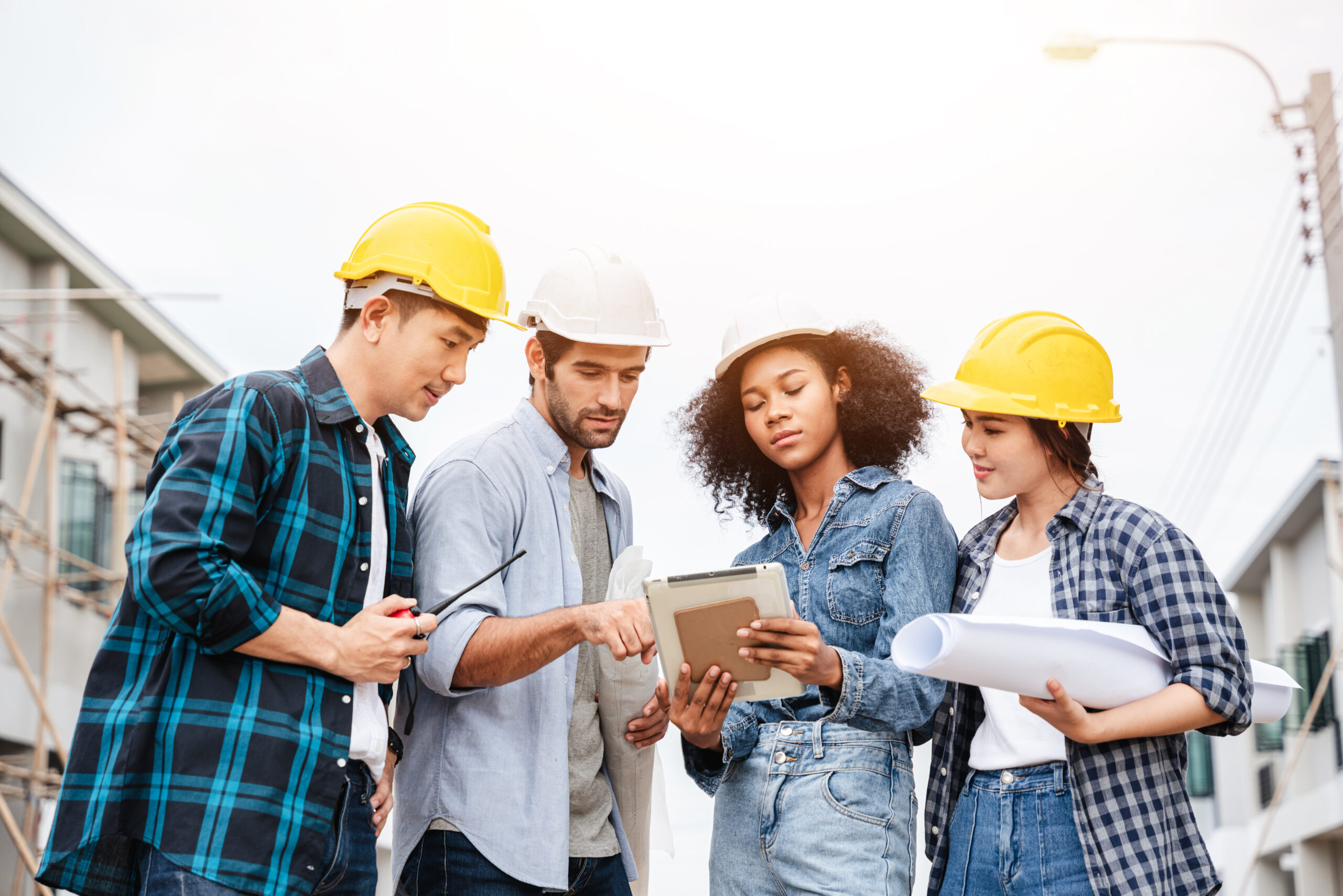 The conversation taking place on the construction site between an architect, an engineer, and a tablet computer displaying a building draft design.